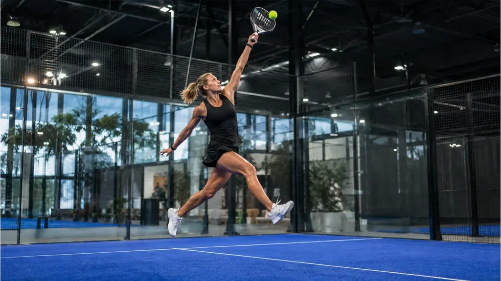 Padel player performing an overhead smash on an indoor court, illustrating common padel injury risks